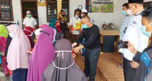 Anggota DPRD Kabupaten Banyuasin, M. Nasir, bersama H. Basyar (kemeja kotak bergaris), menyerahkan sembako kepada masyarakat.
