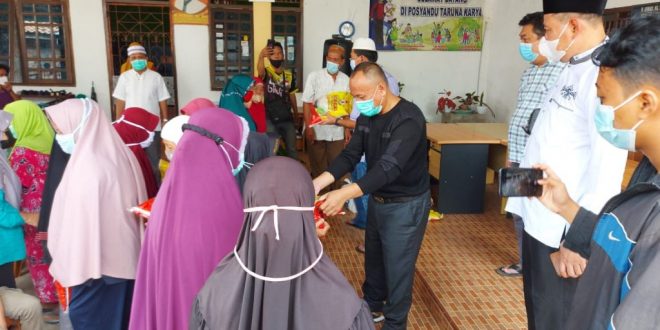 Anggota DPRD Kabupaten Banyuasin, M. Nasir, bersama H. Basyar (kemeja kotak bergaris), menyerahkan sembako kepada masyarakat.