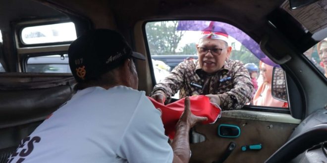 Pj Walikota A Damenta bersama Forum Komunikasi Pimpinan Daerah (Forkompimda) membagikan ribuan bendera merah putih kepada masyarakat dan pengendara yang melintas di Simpang 5 DPRD Sumatera Selatan (Sumsel), Kamis (15/8/2024) pagi.