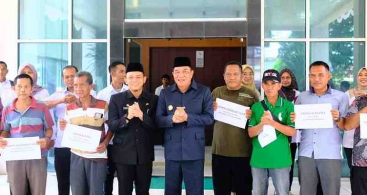 Bupati Musi Banyuasin H M Toha Tohet SH saat menyerahkan bantuan alat pasca panen berupa bak pembekuan getah karet kepada kelompok petani yang tergabung dalam Unit Pengolahan dan Pemasaran Bokar (UPPB), di halaman Kantor Dinas Perkebunan Muba, Rabu (29/10/2025).